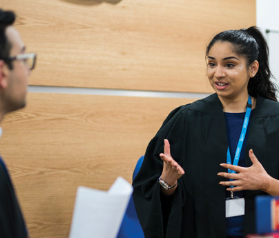 woman wearing black robes with hand movements speaking to man