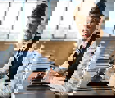 young man smartly dressed sits at boardroom table