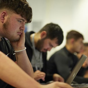 student sat working on laptop in classroom