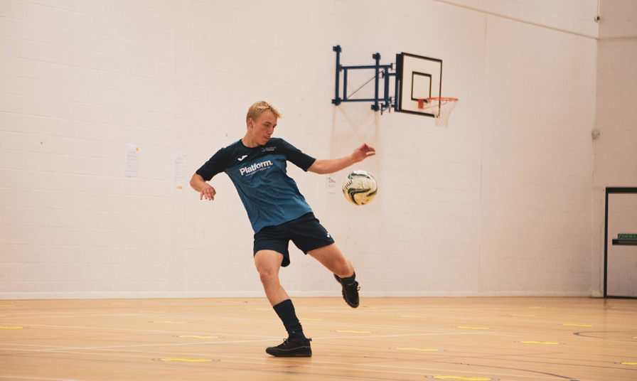 footballer about to kick ball in sports hall