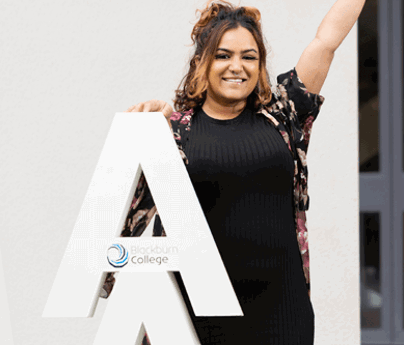 young lady stands behind large A lettering whilst punching in the air