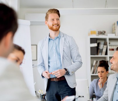 man stands in front of group smiling presenting with flipchart