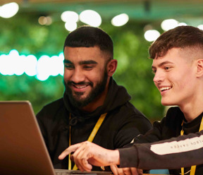 2 young men smiling looking at laptop
