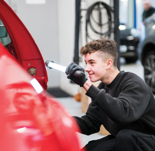 young man examines car in mechanics workshop