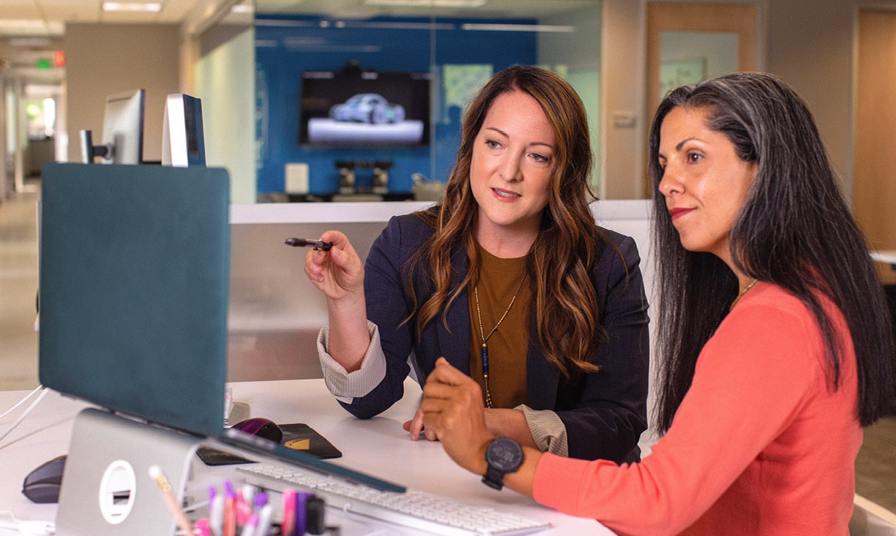 2 women looking and pointing at screen in office