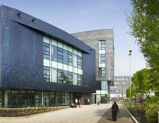 Beacon Centre Blackburn College in sunshine with students stood outside and trees