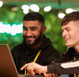 2 young men smiling looking at laptop