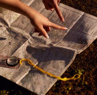 close up of map and compass with hands pointing